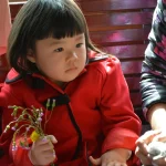 girl in red zip up jacket holding red rose