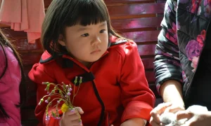 girl in red zip up jacket holding red rose